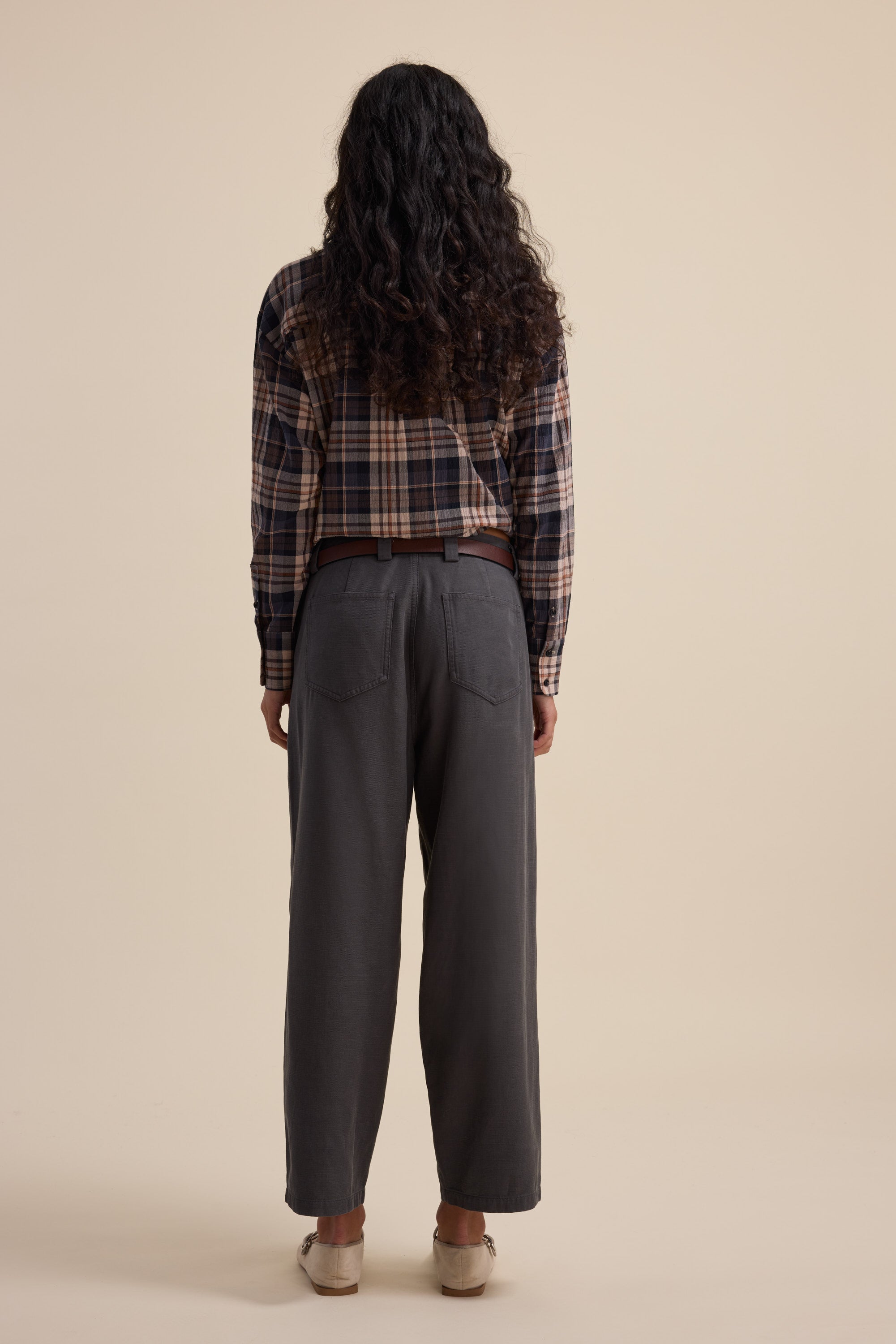 Person with long curly hair wearing Elementary Panelled Barrel Pants, facing away.