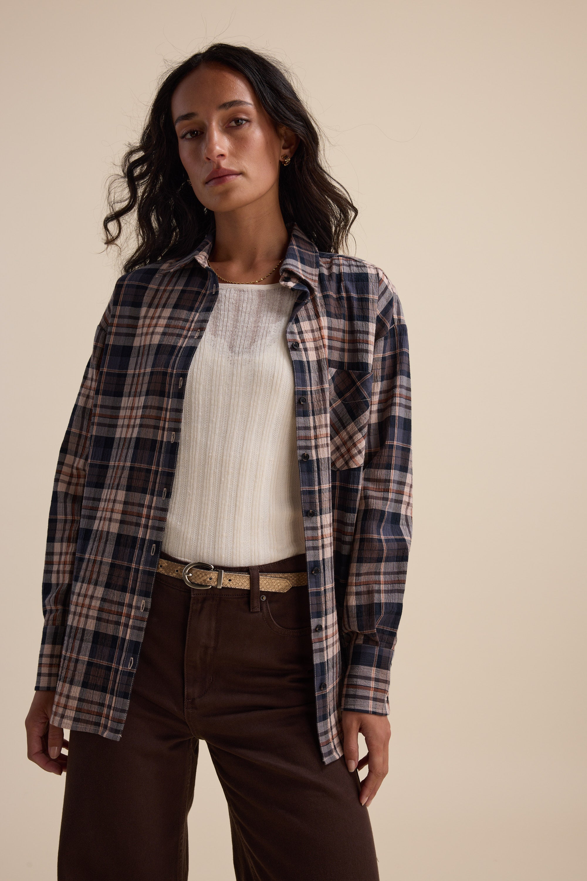 Woman wears Elementary Knitted Layering Top and brown pants, posed against a beige background.