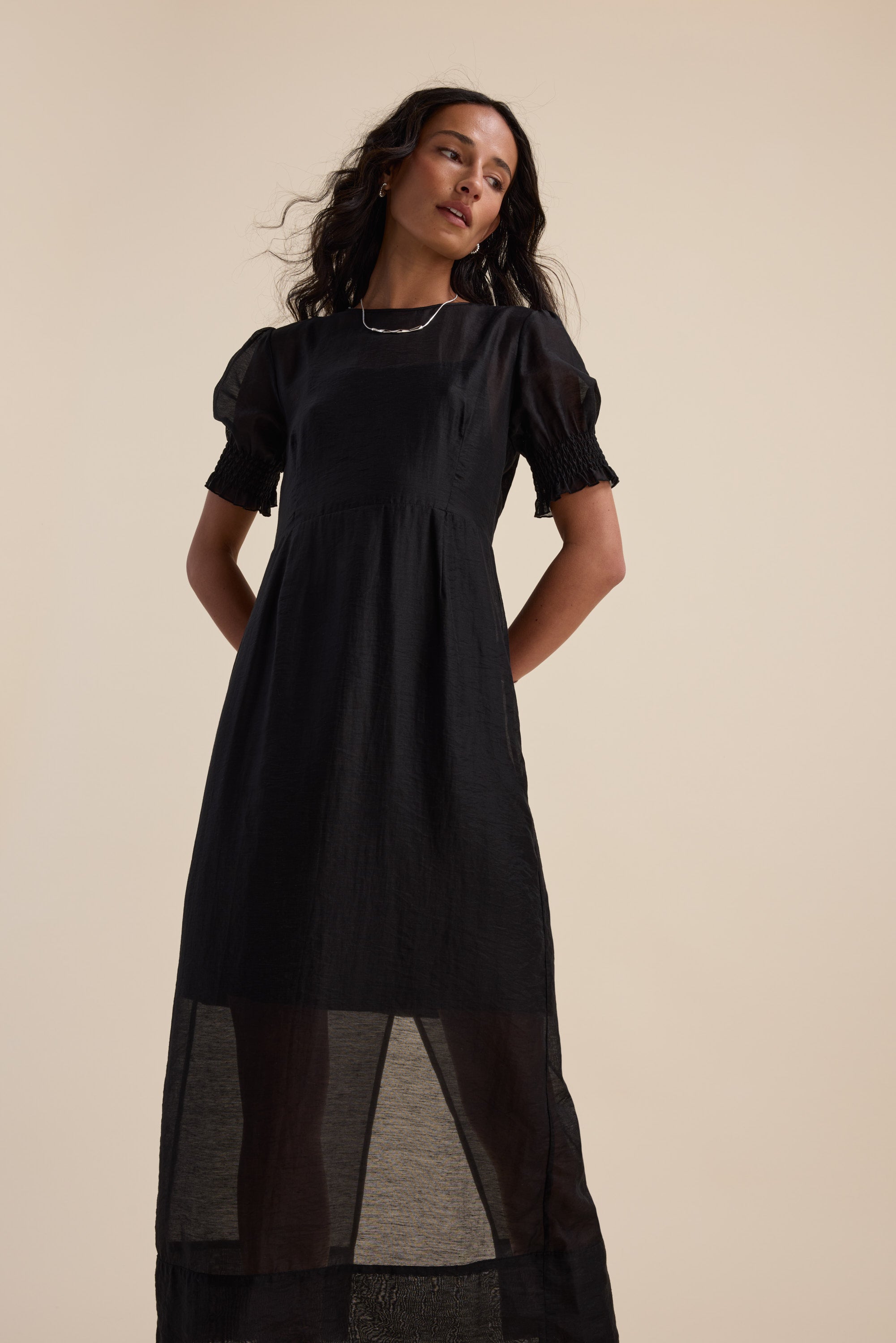 Max's The Sheer Layering Dress in black, short sleeves, shown against a beige background.