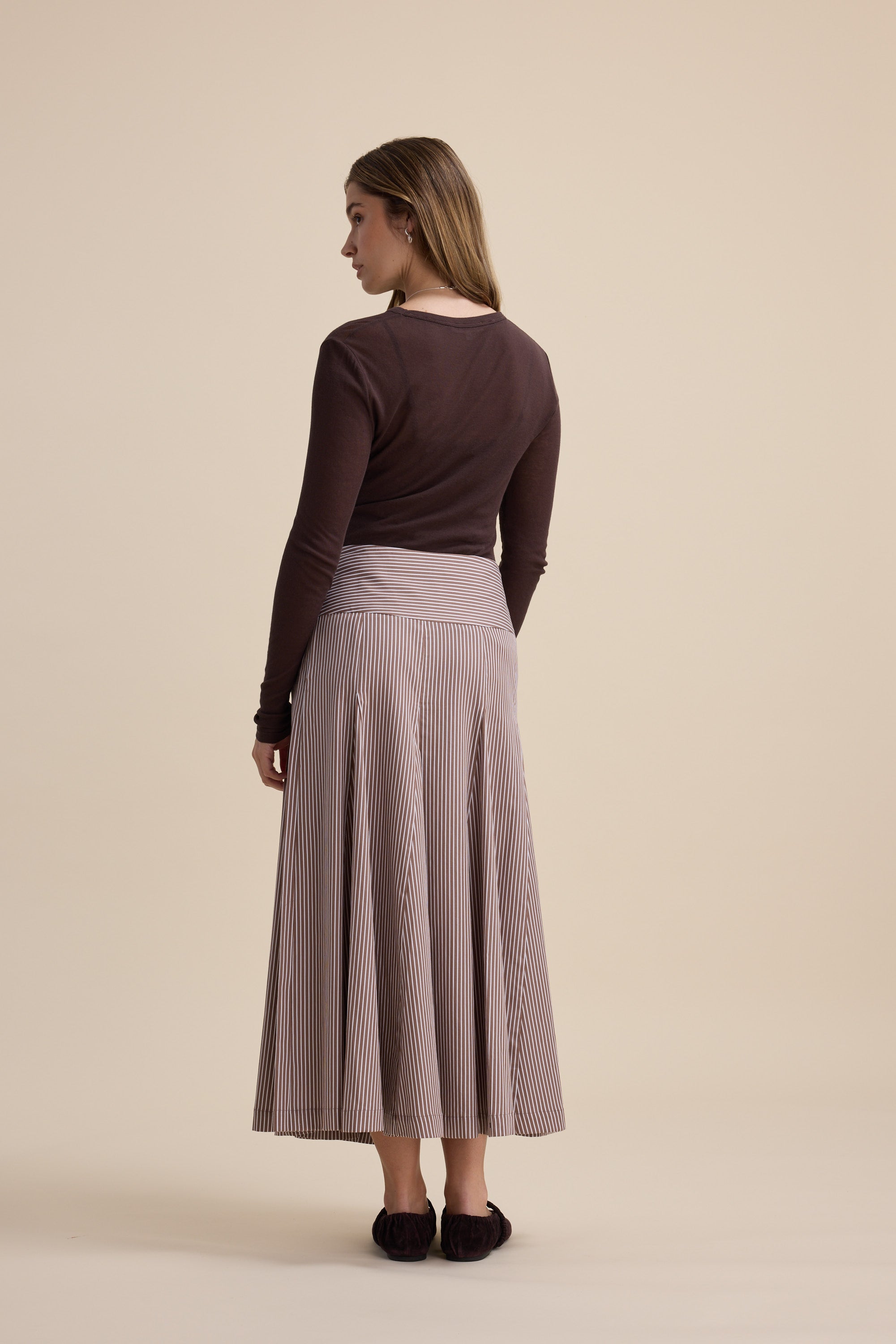 Woman in brown top and Max Marley Panel Seam Skirt, organic cotton, midi length, neutral backdrop.