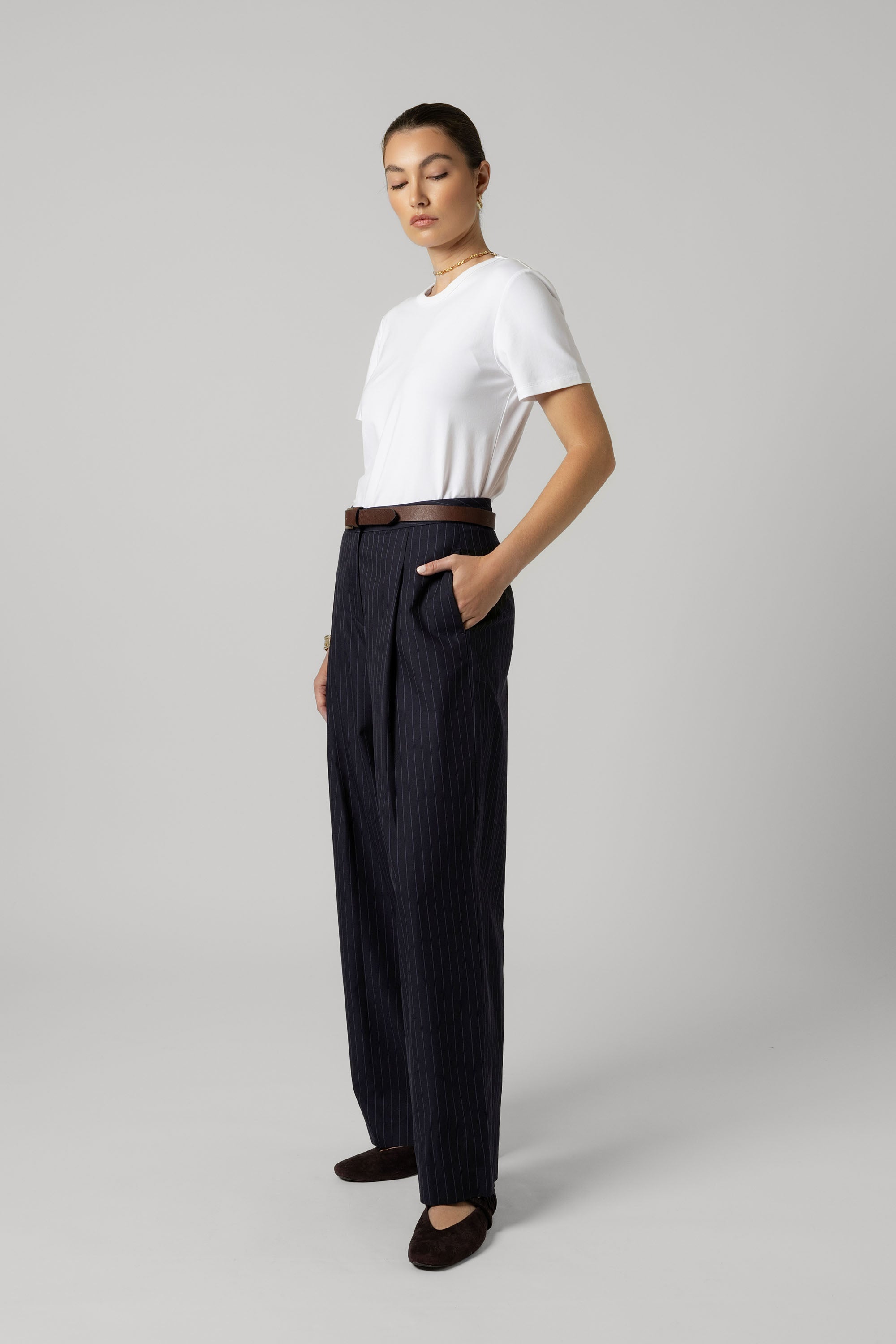 Woman in The Pleat Detail Wide Leg Pants by Max, white tee, and black shoes in studio.