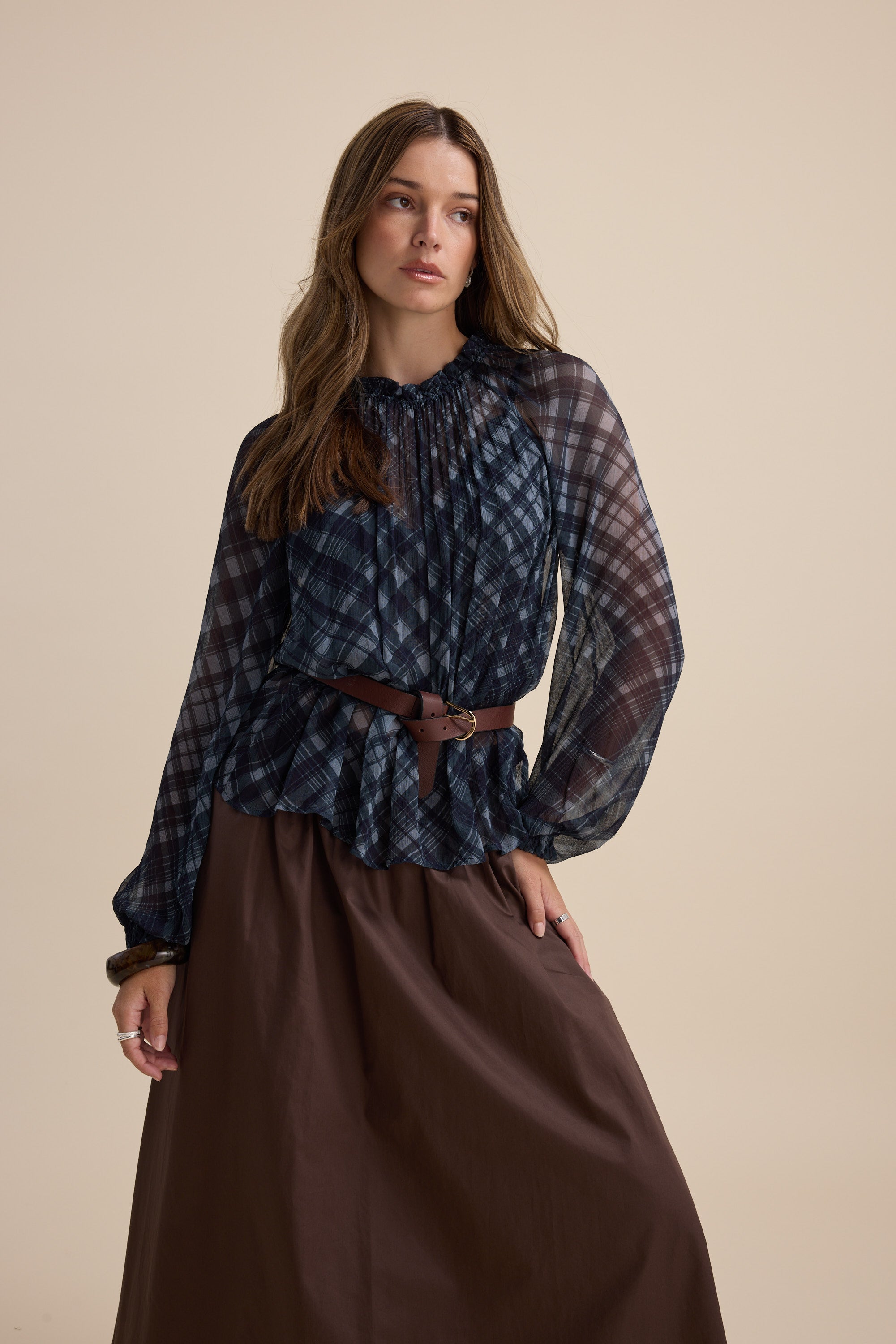 Woman in Max’s Quinn Gather Detail Blouse and brown skirt poses against a beige background.