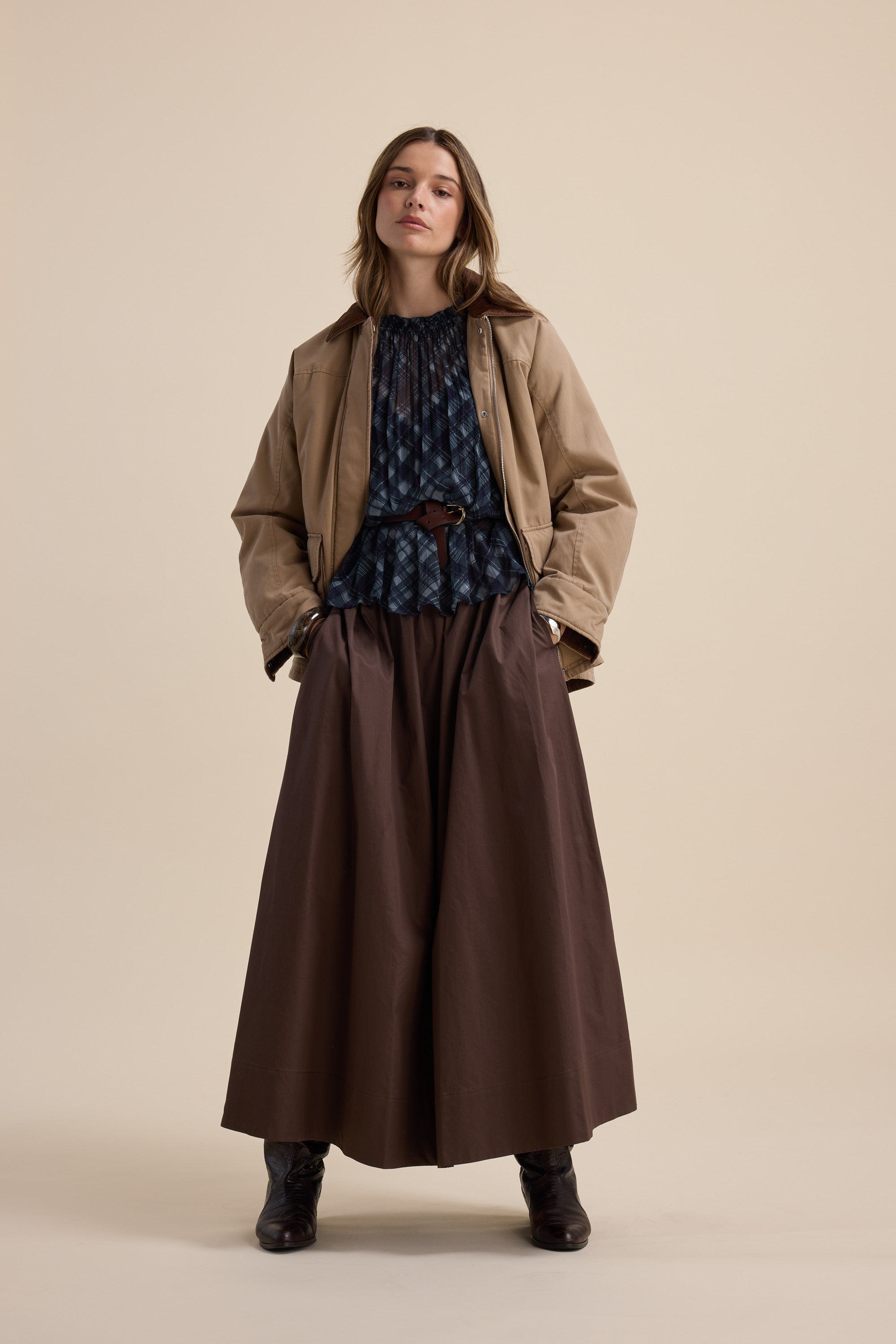 Woman in Max Quinn Gather Detail Blouse, tan jacket, brown skirt, and black boots stands confidently.