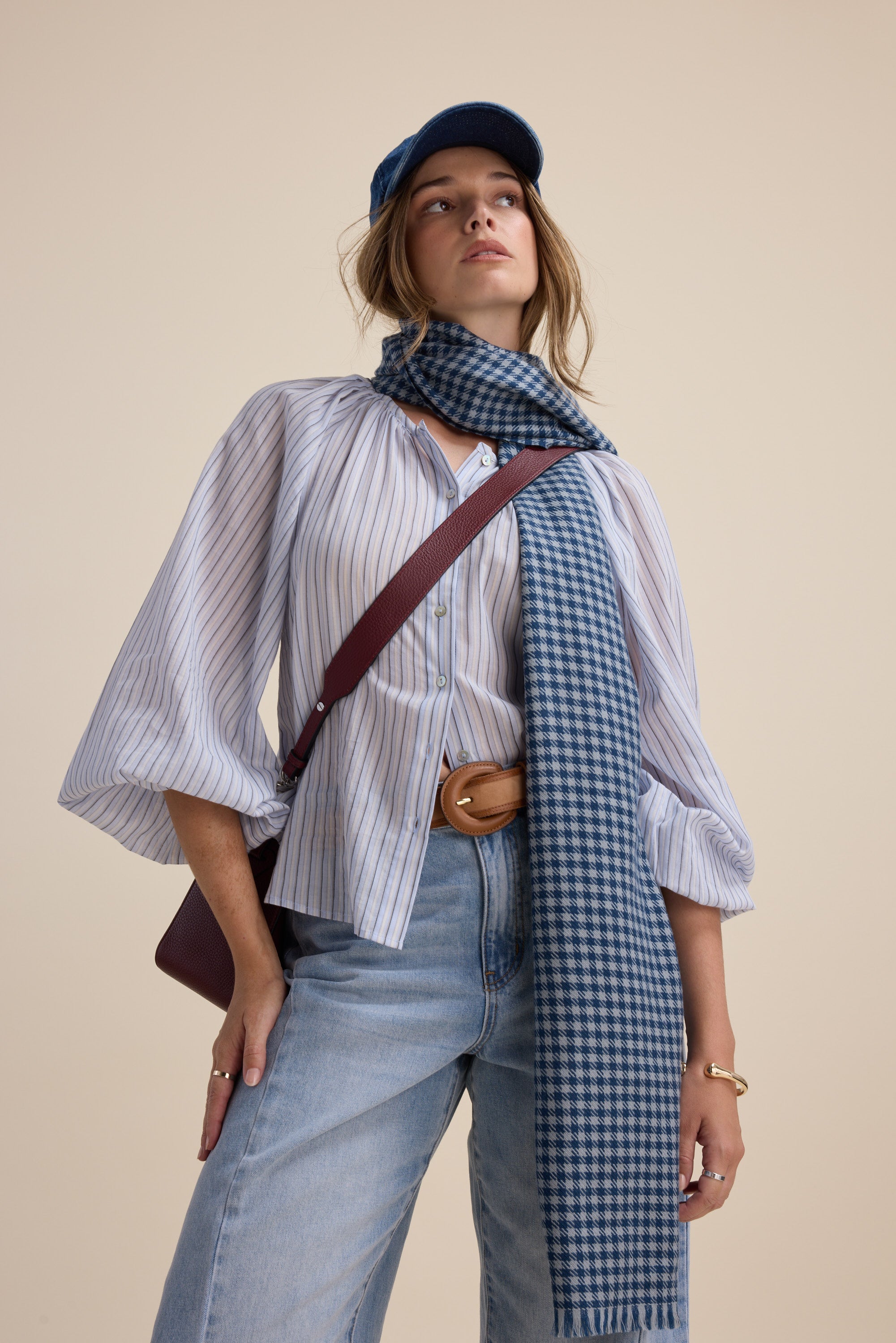 Woman in Max Vivian Button Front Blouse, jeans, blue scarf, cap, and crossbody bag.