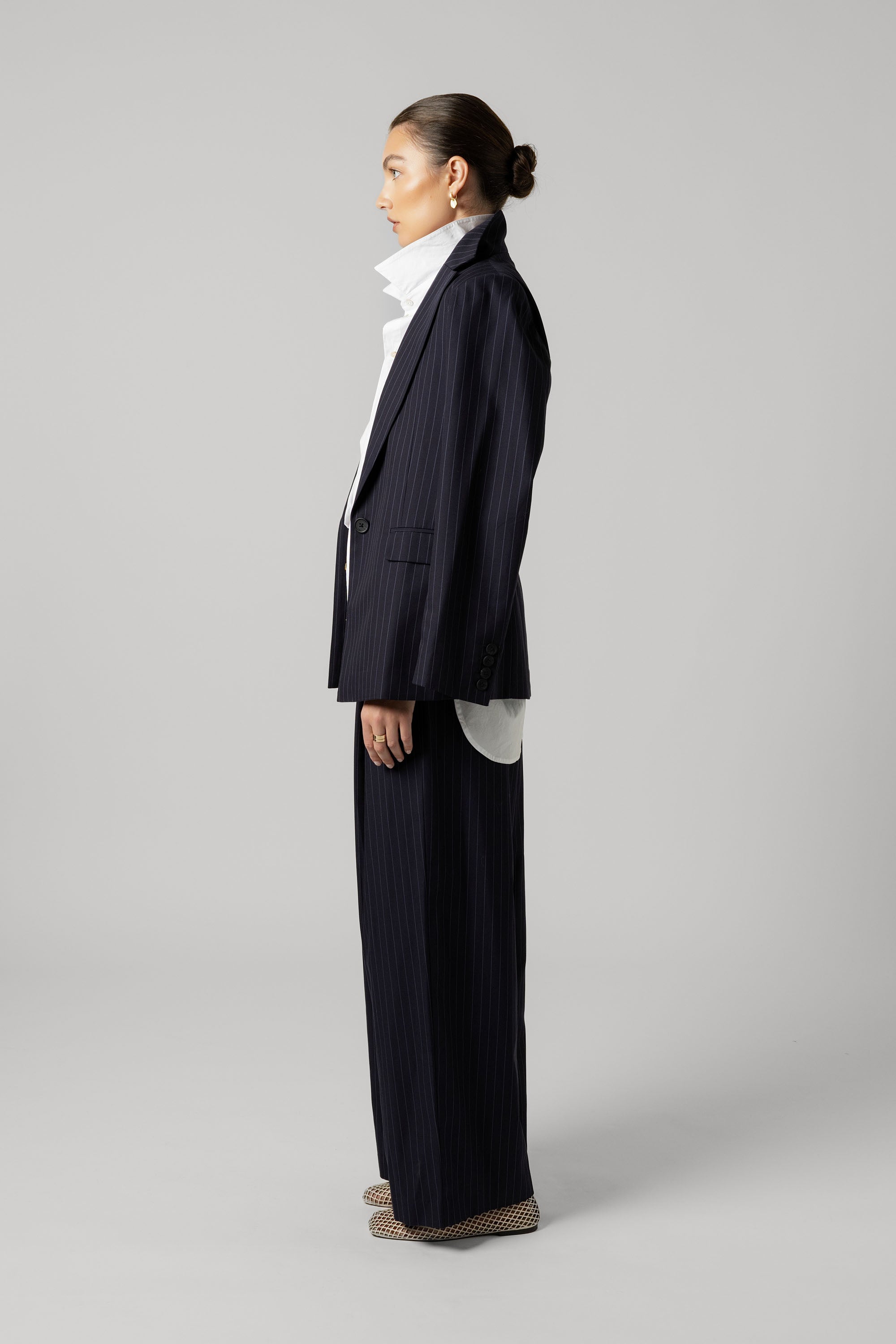Woman in Max's The Pleat Detail Wide Leg Pants, high-collared shirt, shown in profile.