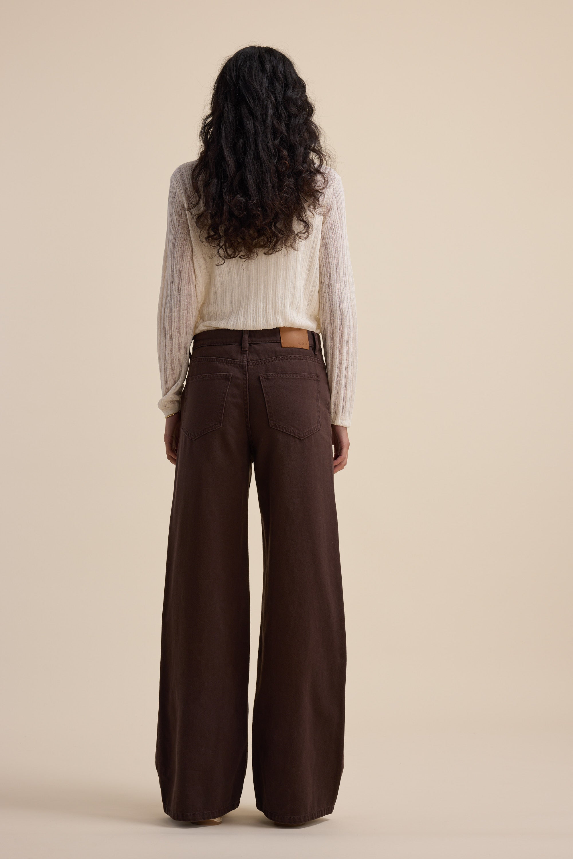 Person in a cream sweater and Max Alaska Wide Leg Jeans, standing against a beige background.
