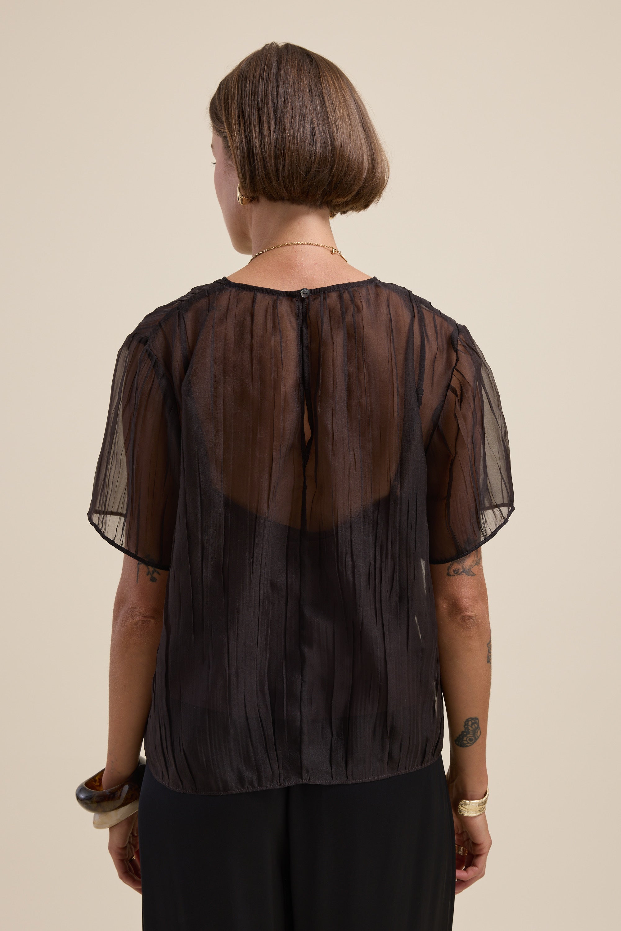 Model wears the Cass Sheer Top by Max, cropped fit, shown from the back on a plain backdrop.