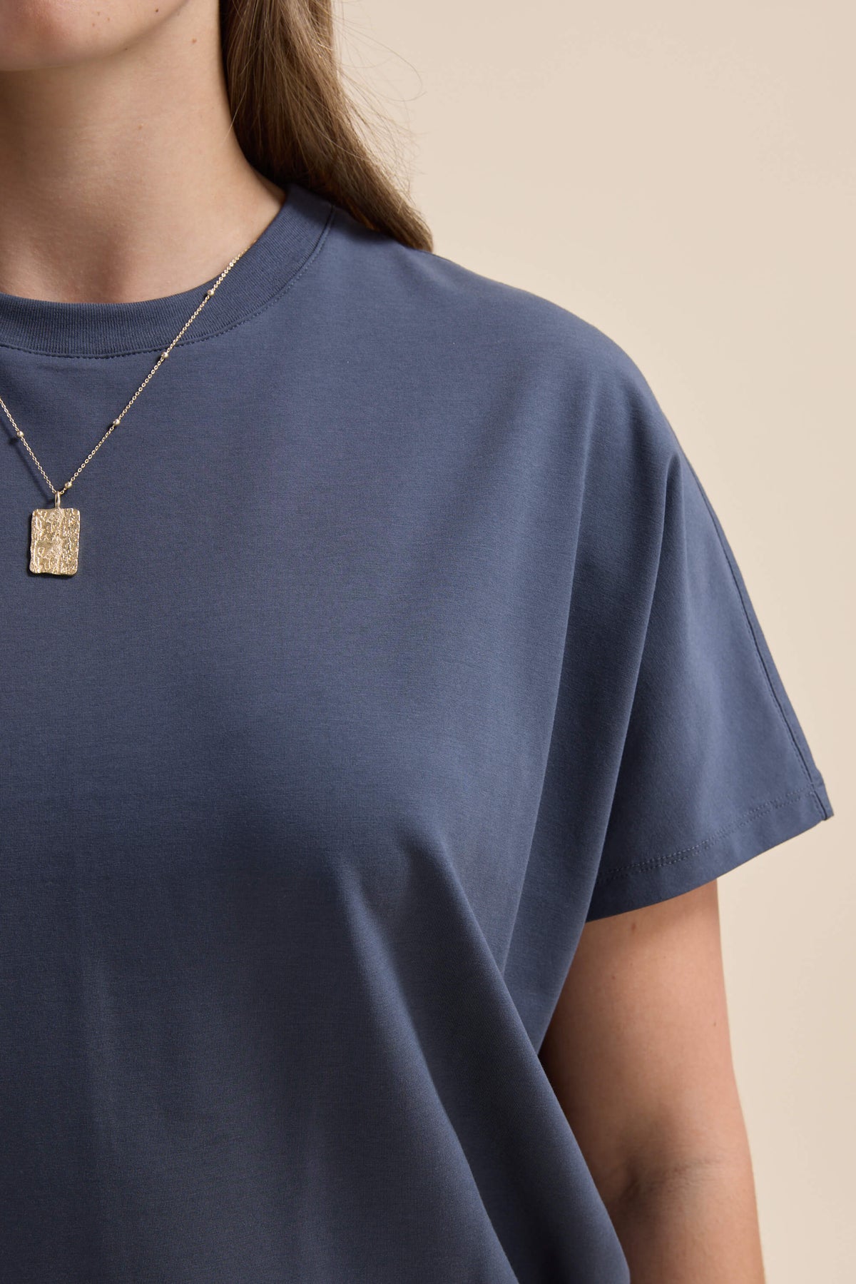 Woman in Elementary Slouchy Short Sleeve Tee, blue, styled with a gold rectangular pendant.