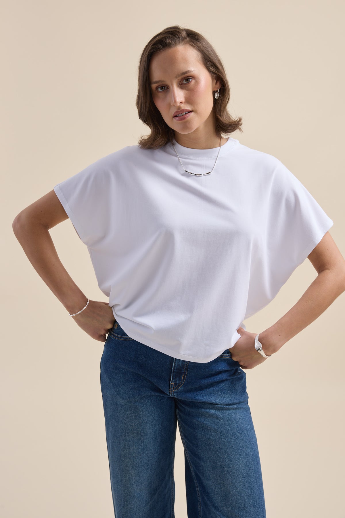 Woman in an Elementary Slouchy Short Sleeve Tee and blue jeans stands with hands on hips.