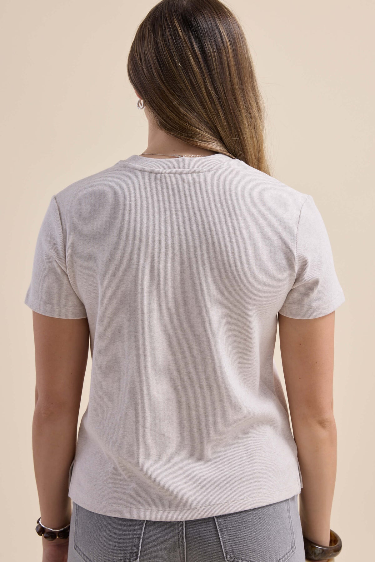 Person with long hair in a ribbed boxy gray Elementary tee, shown from the back.