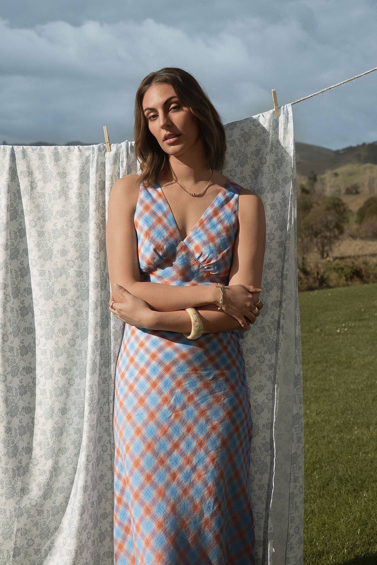 Woman wears Max Nina Bias Cut Dress outdoors, arms crossed, grassy field and sheet behind her.