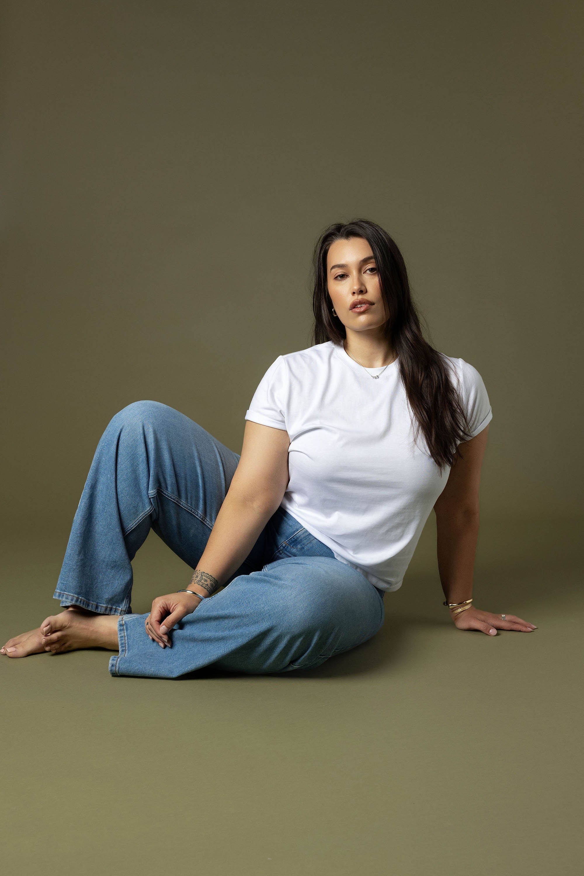 Woman in a white tee and Max Nevada Wide Jeans sits against a plain background.
