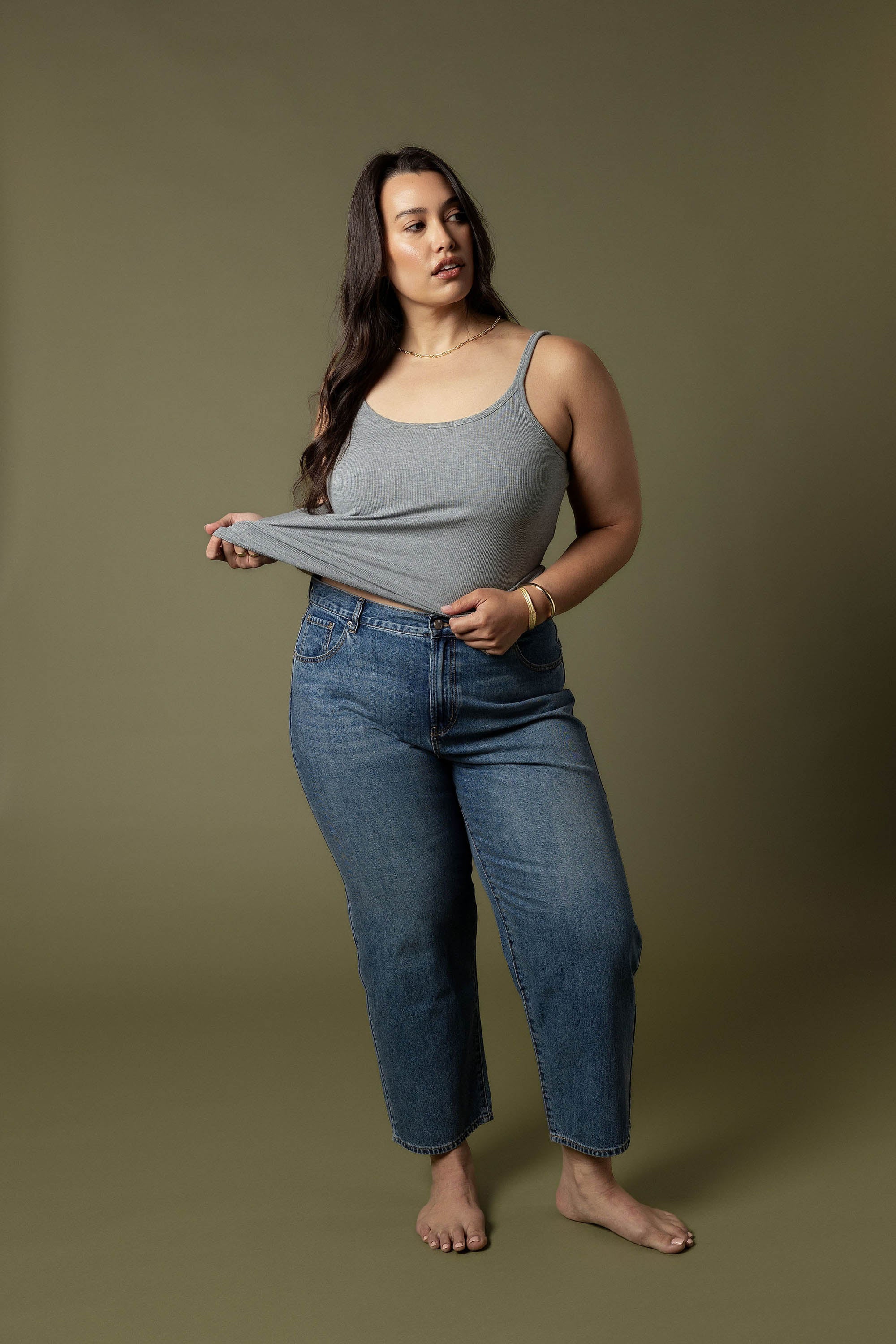 Max Borrowed From The Boys Jeans styled with a grey tank top, model stands barefoot.