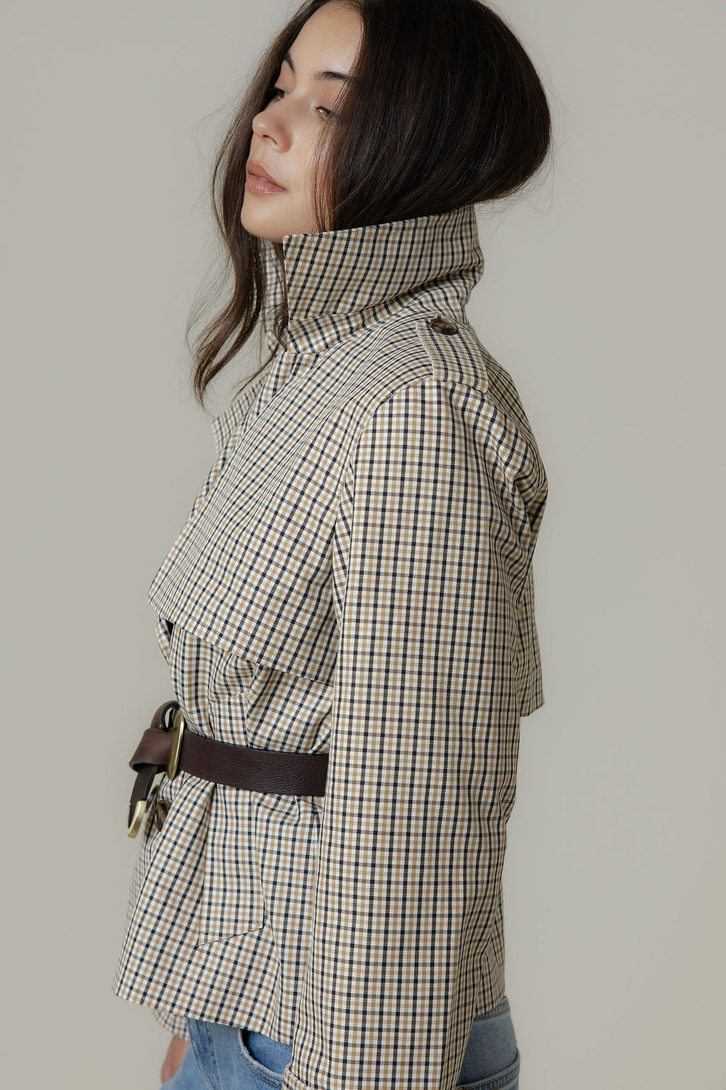 Woman in Max’s The Cropped Trench Coat, sustainable fabric, high collar, belt, facing left.