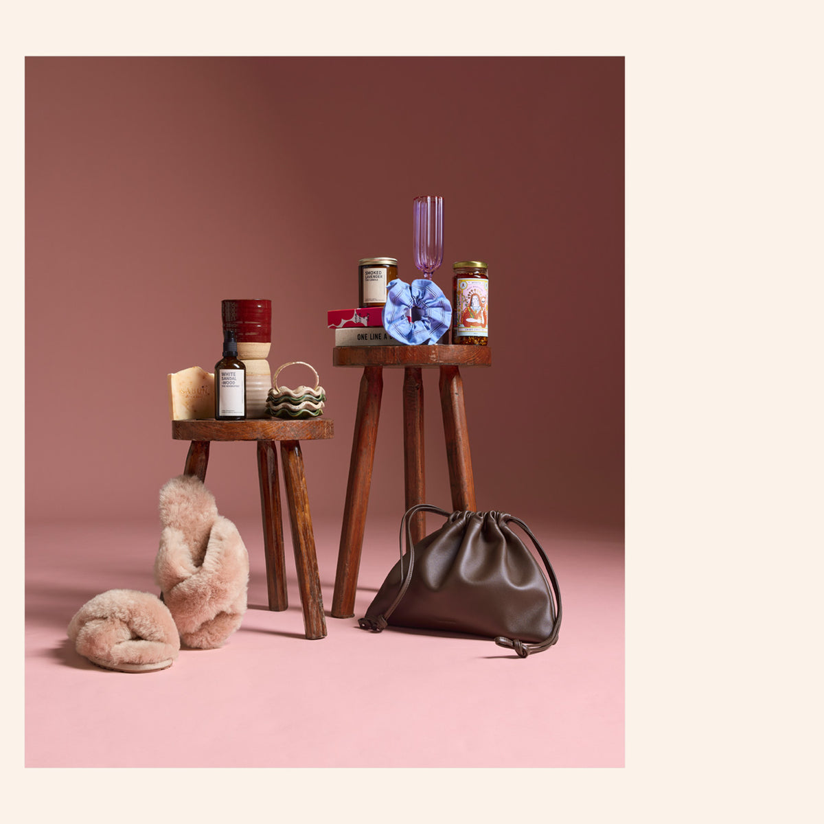 Two small wooden stools with NZ food, drink, slippers, a purple glass, and a brown handbag.