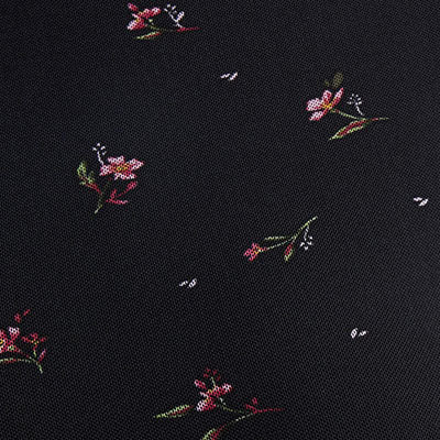 NZ-inspired black fabric with scattered pink and red flowers and green leaves.