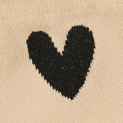 A black heart shape on a beige fabric background, inspired by NZ minimalism.